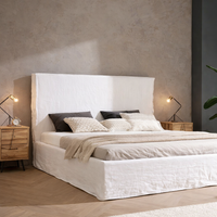 Custom upholstered bed with white linen headboard in a bright Mediterranean bedroom in Mallorca