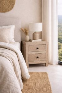 Mango wood bedside table next to a neutral linen bed in a bright Mediterranean style bedroom.