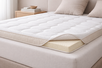 Natural latex mattress topper with rounded edges and beige satin side panel on upholstered bed