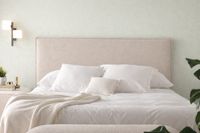 CARTIER upholstered headboard in natural beige fabric with removable cover, styled with white bedding against a soft sage wall i